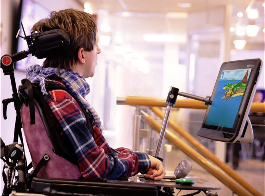 En ung mann med cerebral parese bruker et øyekontrollert apparat fra Tobii Dynavox til å spille spill.